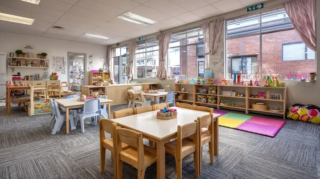 Spotless clean childcare classroom with timber tables, colourful play mats and natural light